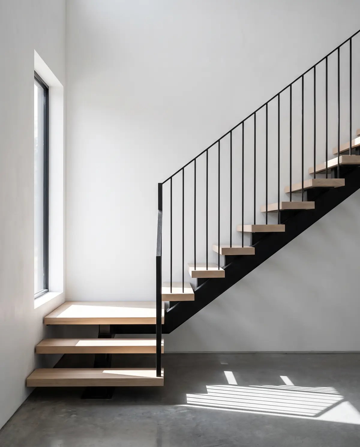 A floating white oak staircase with a blackened steel stringer